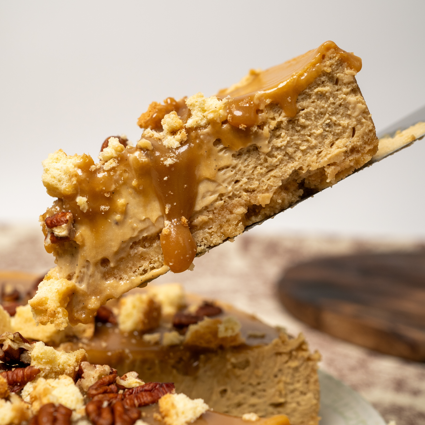 Momento de disfrutar un Salted Caramel Cheesecake, con una porción levantándose que muestra su relleno indulgente.